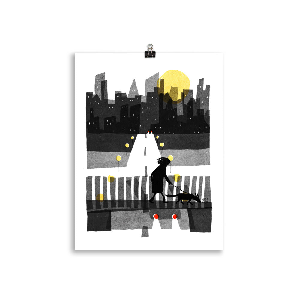 Over art print by Magda Brol: a woman walking her dog over a bridge with white railings at night, under a yellow moon and city skyline, unframed print hanging from a clip